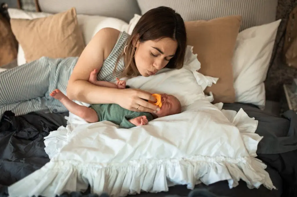 A mother putting pacifier in her baby's mouth