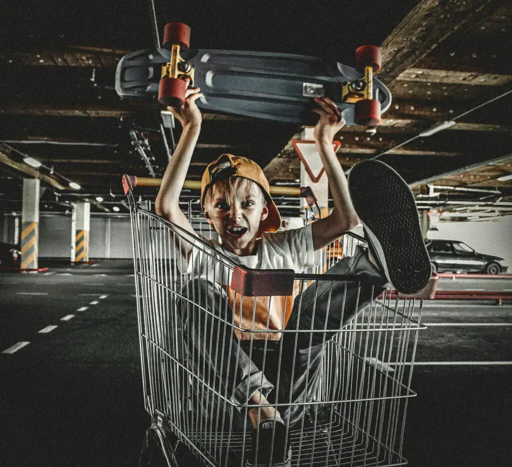 Boy Holding a Penny Board in a Push Cart