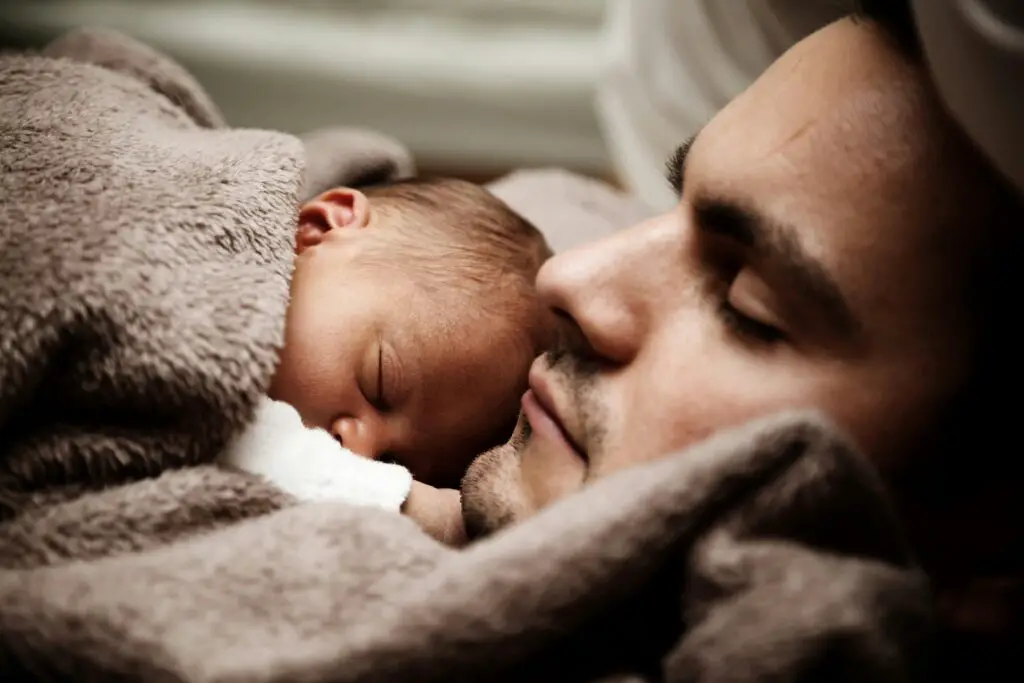 A touching close-up of a father and his baby peacefully napping together.