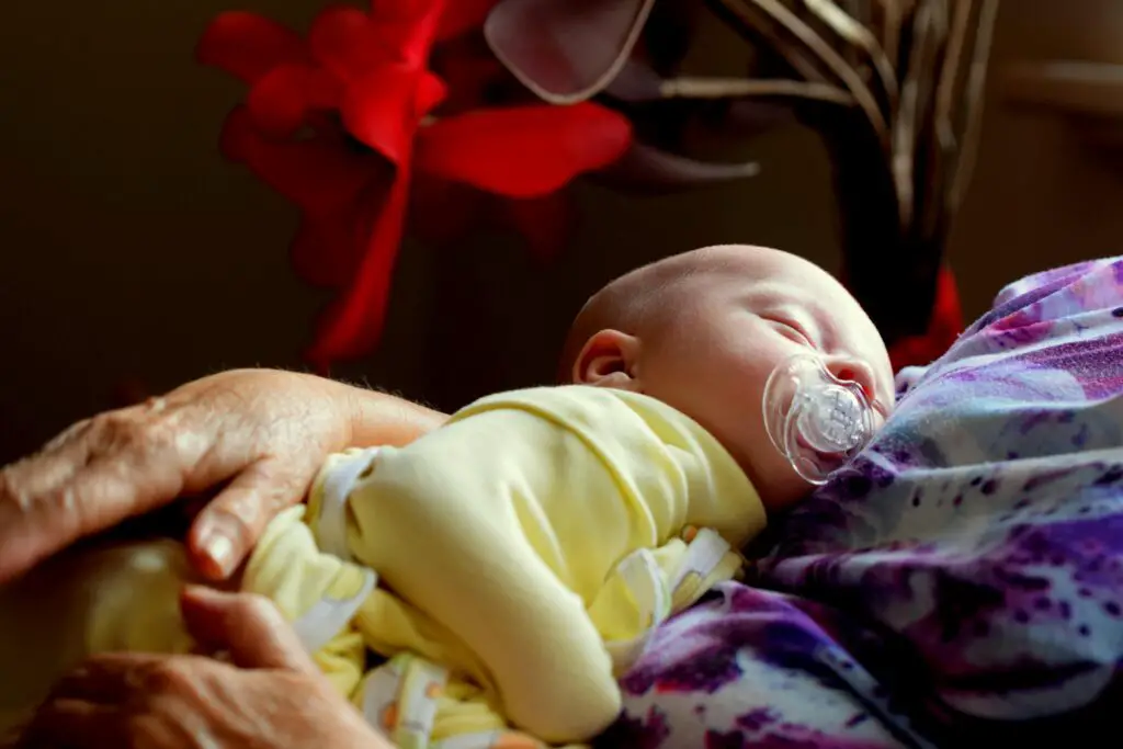 A peaceful newborn sleeping in a woman's embrace, surrounded by cozy warmth.