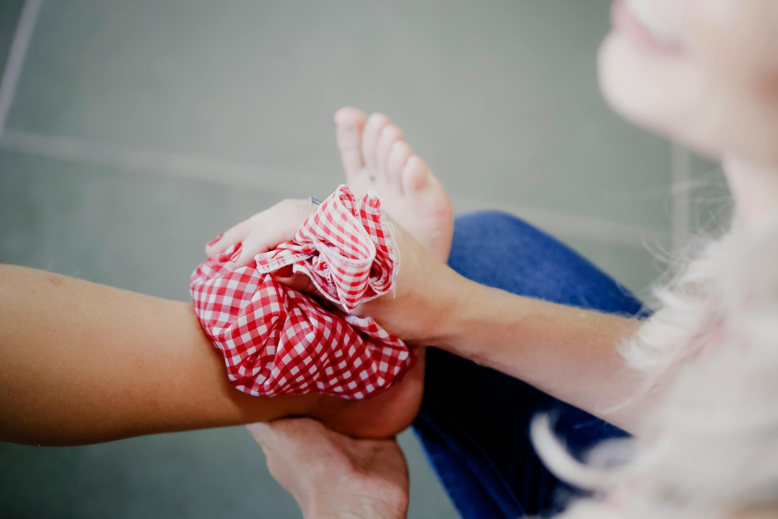 Close-up of a person using a checkered ice pack on an injured ankle, promoting injury care and relief.