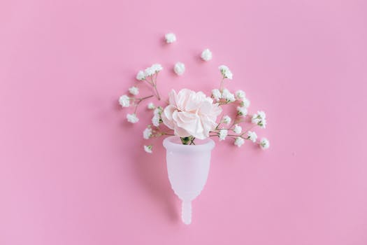 pexels-photo-5712300-5712300 A menstrual cup filled with delicate flowers on a pink background, symbolizing feminine care and eco-friendly solutions.