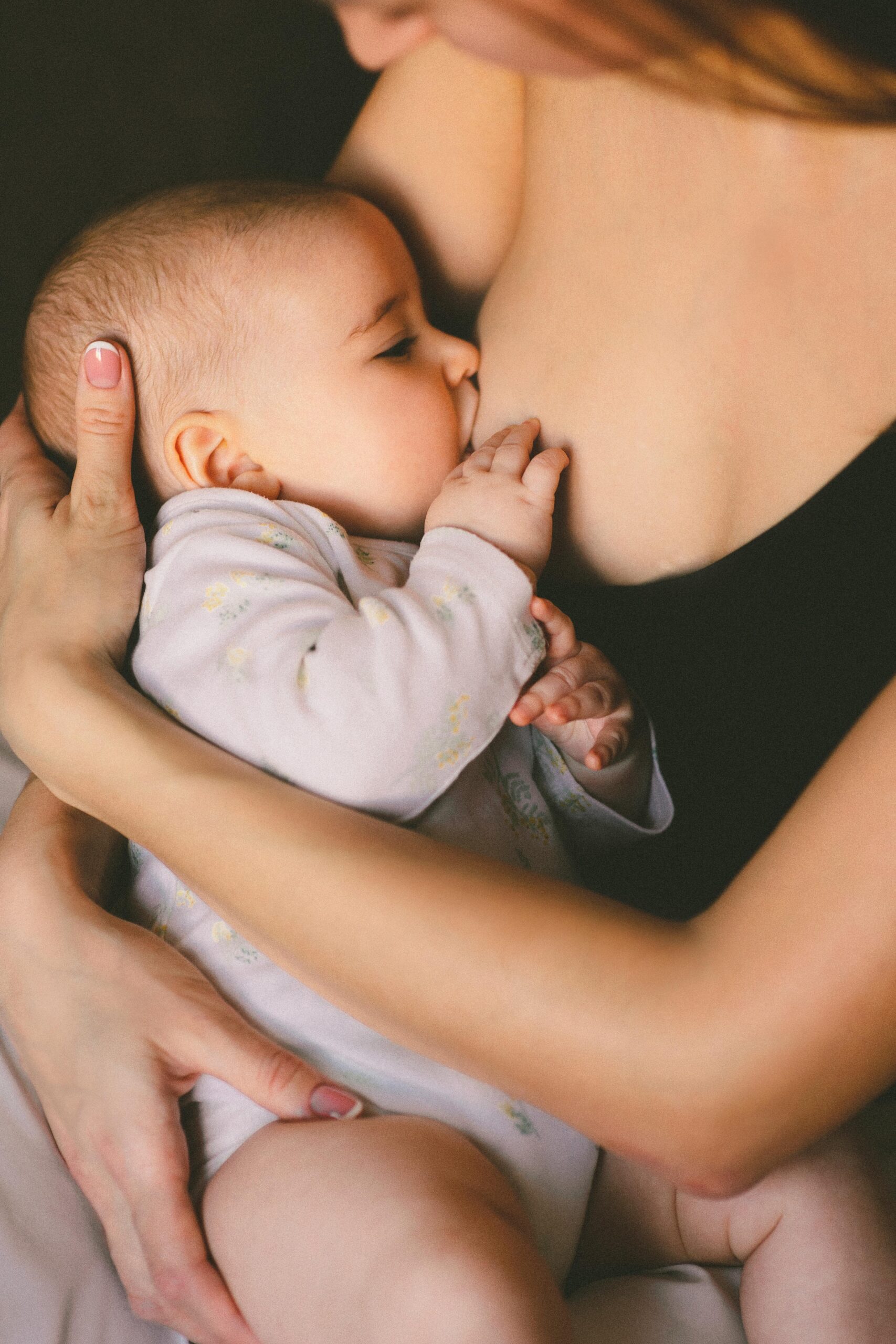 A close-up of a mother lovingly breastfeeding her baby, symbolizing care and motherhood.