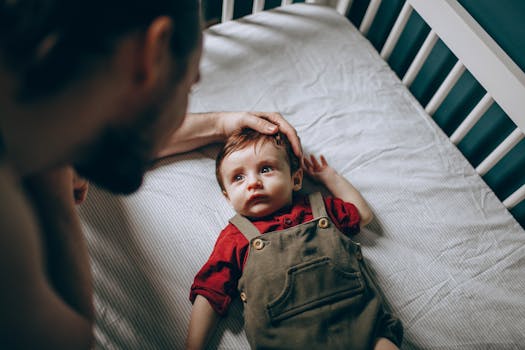 pexels-photo-6957487-6957487 A father lovingly caresses his baby in a crib, showcasing a tender moment of parenthood.